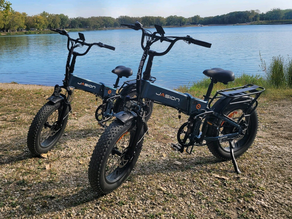 Two Jasion X-Hunter fat tire electric bikes parked on a gravel lakeshore, showing real-world ebike parking and the importance of securing your bike when stopped outdoors