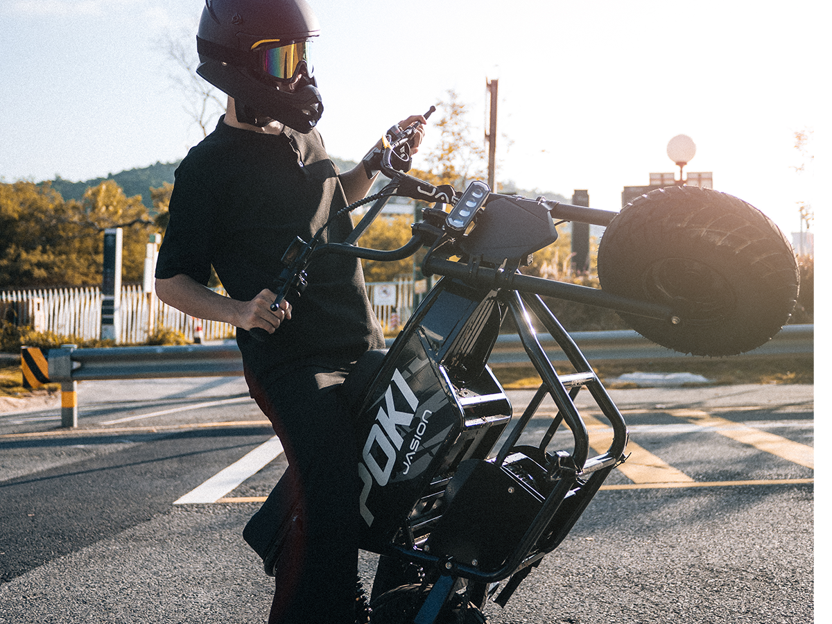 Helmeted rider performing a wheelie on a black Jasion Poki Electric Mini Bike outdoors