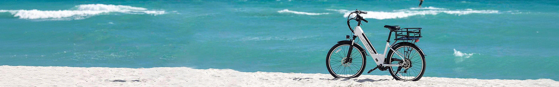 Jasion EB5 Roamer electric bike parked on sandy beach with turquoise ocean waves in background